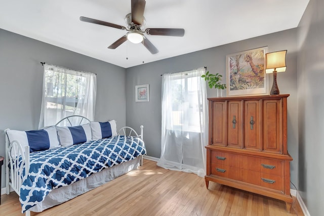 bedroom with light wood finished floors, ceiling fan, and baseboards