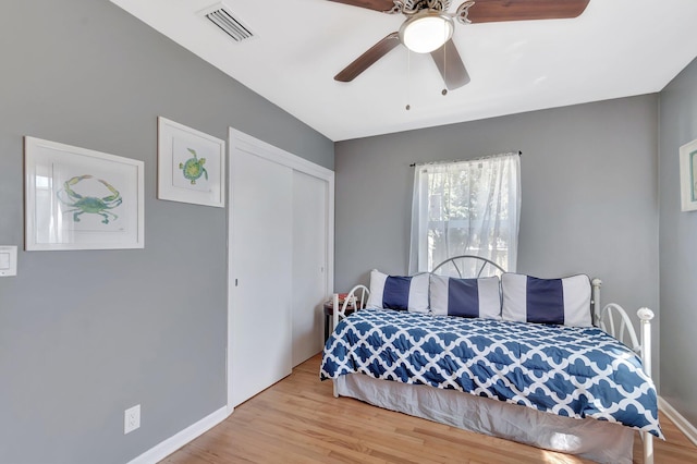 bedroom with visible vents, baseboards, a closet, and wood finished floors