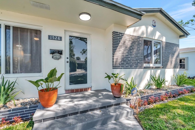 entrance to property with covered porch and stucco siding