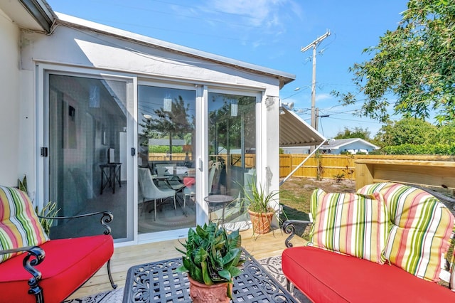 view of patio featuring a wooden deck, a sunroom, and fence