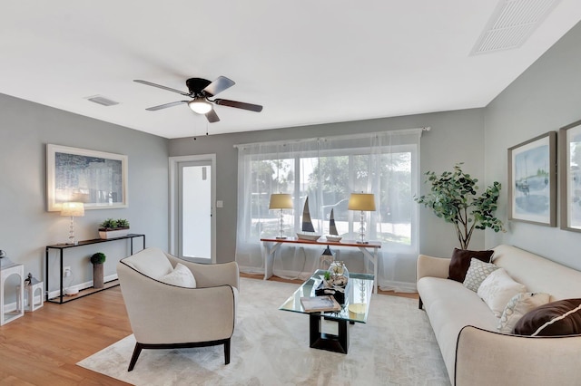 living area with ceiling fan, visible vents, baseboards, and wood finished floors