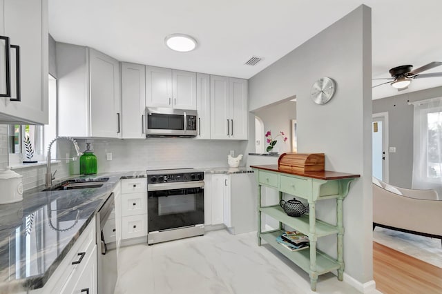 kitchen featuring a sink, light stone counters, visible vents, and stainless steel appliances