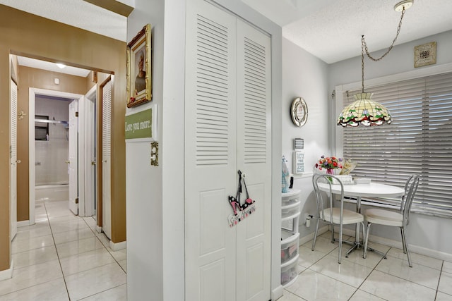 dining area featuring light tile patterned flooring, baseboards, and a textured ceiling