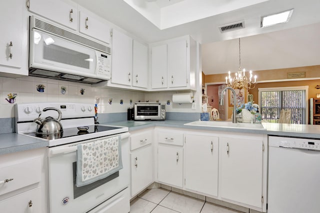 kitchen with white appliances, visible vents, an inviting chandelier, a sink, and backsplash