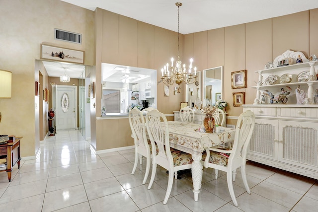 dining area featuring light tile patterned floors, baseboards, visible vents, and a towering ceiling