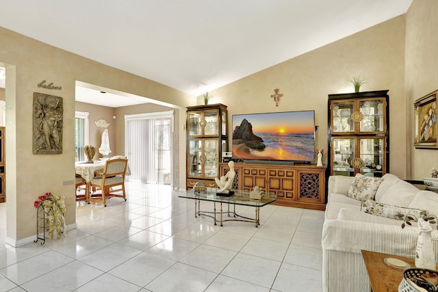 living room featuring lofted ceiling, light tile patterned floors, and baseboards