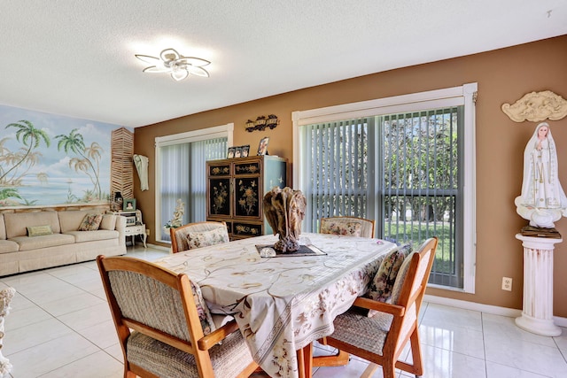 dining space with light tile patterned floors, a textured ceiling, and baseboards