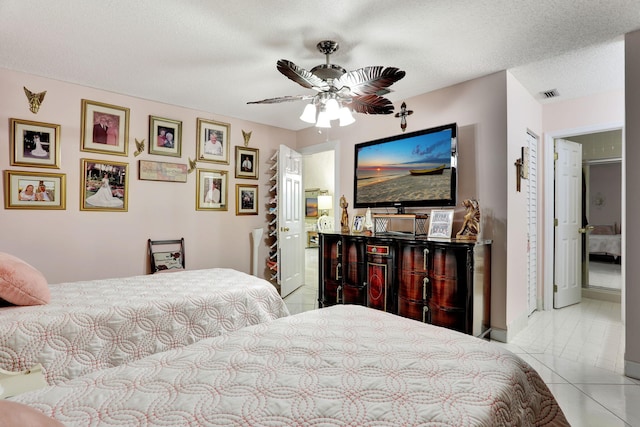 bedroom featuring visible vents, baseboards, tile patterned floors, a textured ceiling, and a ceiling fan