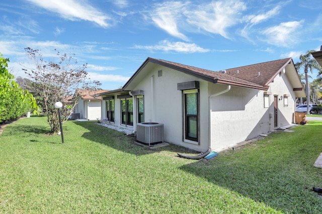 view of side of property with cooling unit, a yard, and stucco siding