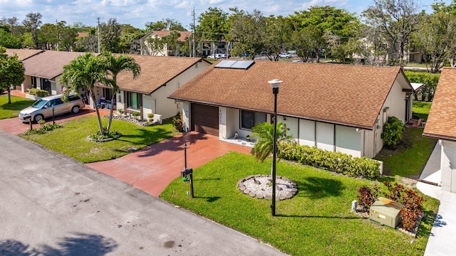 ranch-style home with a residential view, a front yard, stucco siding, driveway, and an attached garage