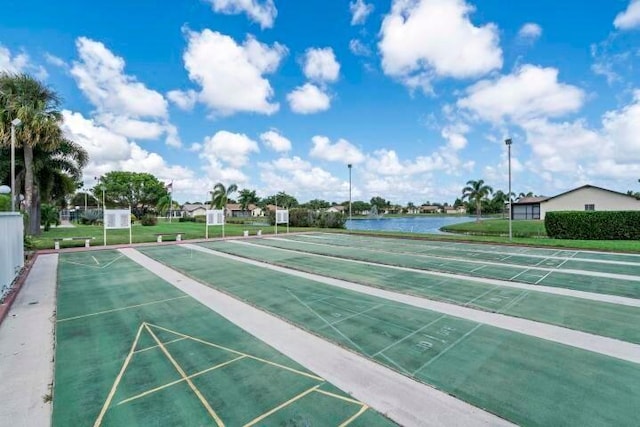 view of property's community featuring a yard, a water view, and shuffleboard