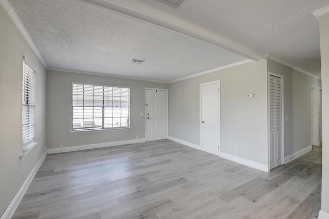 empty room featuring crown molding, light wood-style flooring, baseboards, and a textured ceiling