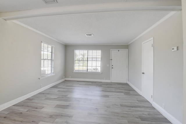 empty room with a textured ceiling, light wood-style flooring, visible vents, and ornamental molding