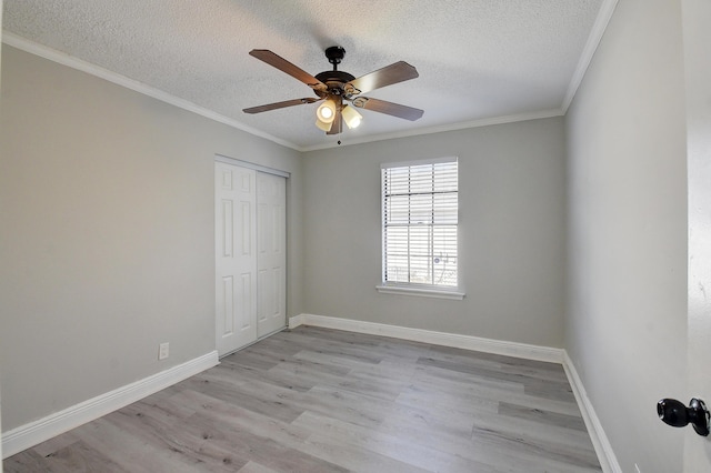 unfurnished bedroom featuring a closet, baseboards, light wood-style floors, and crown molding