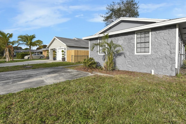 view of front of home featuring stucco siding, driveway, a front lawn, and fence