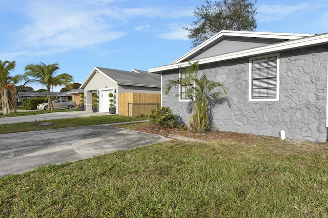 view of side of property with stucco siding, a yard, driveway, and fence