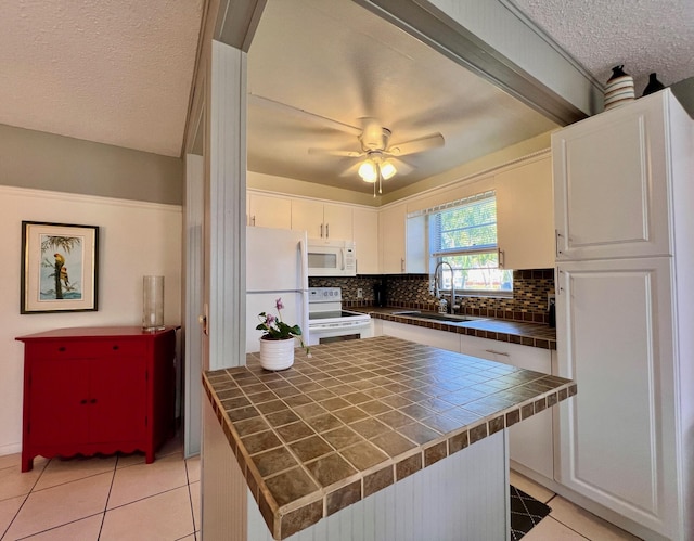 kitchen with white appliances, tile countertops, light tile patterned floors, a sink, and tasteful backsplash