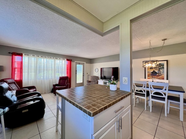 kitchen featuring light tile patterned floors, tile counters, open floor plan, and white cabinetry