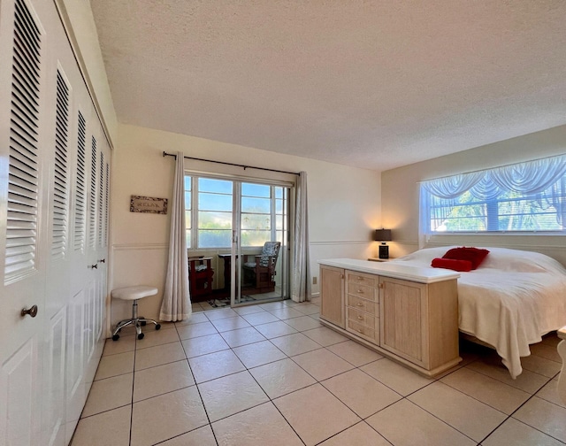 bedroom featuring light tile patterned floors, a textured ceiling, and access to exterior