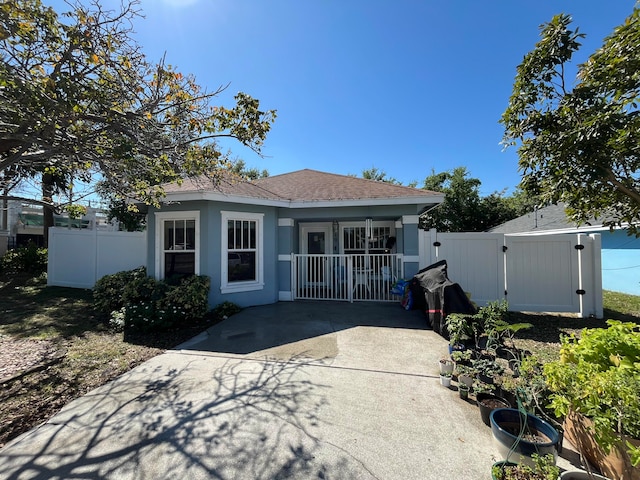 back of property with a gate, fence, stucco siding, a shingled roof, and concrete driveway