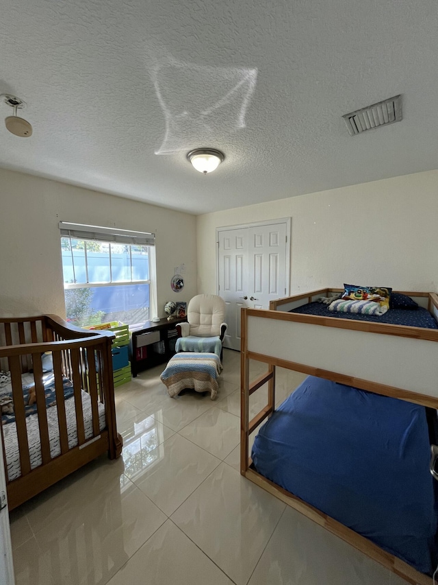 bedroom featuring tile patterned floors, visible vents, and a textured ceiling