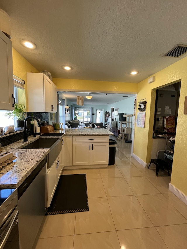 kitchen with visible vents, open floor plan, a peninsula, white cabinetry, and a sink