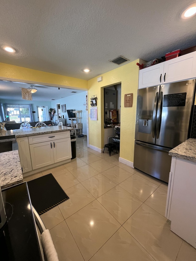 kitchen with visible vents, white cabinets, stainless steel refrigerator with ice dispenser, a textured ceiling, and open floor plan