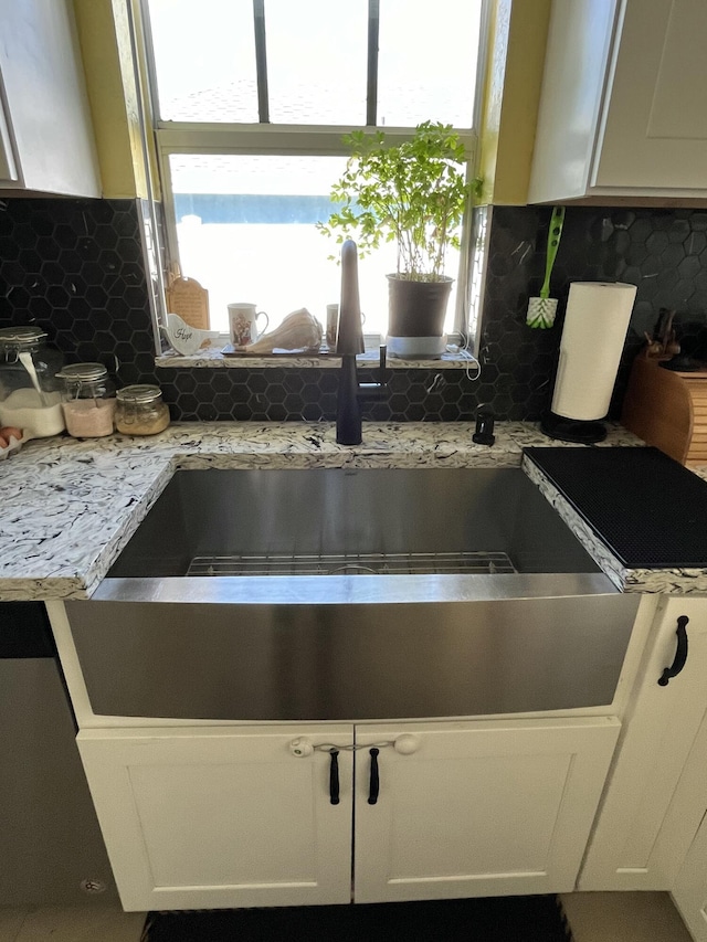 details featuring backsplash, white cabinets, light countertops, and a sink