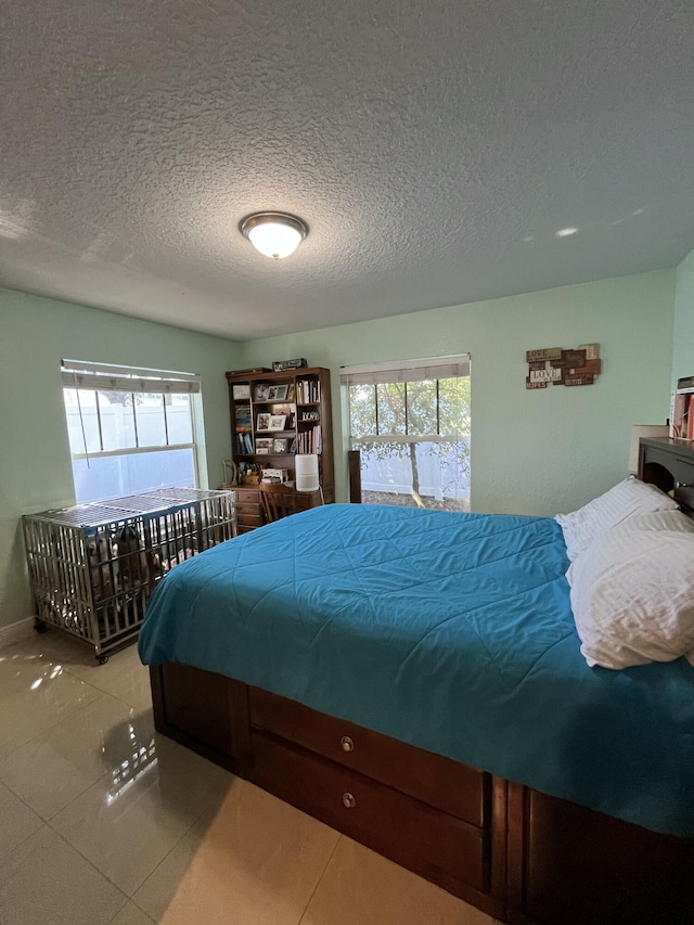 bedroom featuring multiple windows, a textured ceiling, and tile patterned flooring