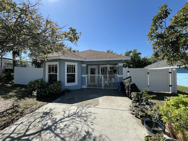 back of house with stucco siding, driveway, a gate, fence, and a shingled roof