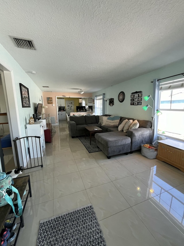 living room featuring a wealth of natural light, visible vents, and light tile patterned floors