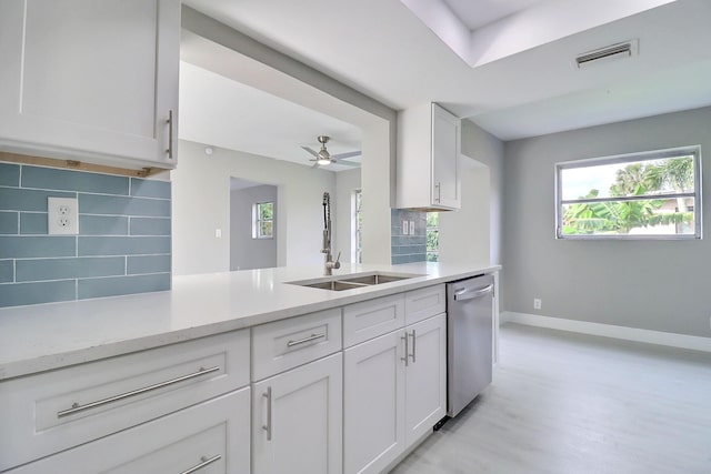 kitchen featuring tasteful backsplash, visible vents, dishwasher, white cabinetry, and a sink