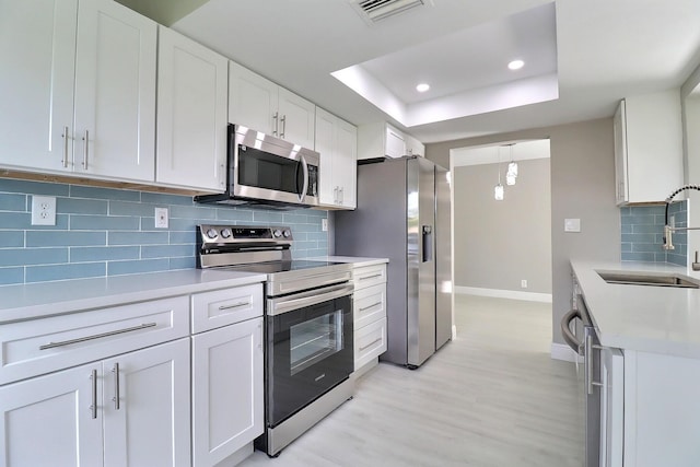 kitchen with visible vents, a sink, appliances with stainless steel finishes, light countertops, and a raised ceiling