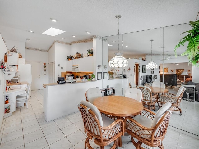 dining room featuring light tile patterned floors, recessed lighting, a skylight, a high ceiling, and a textured ceiling