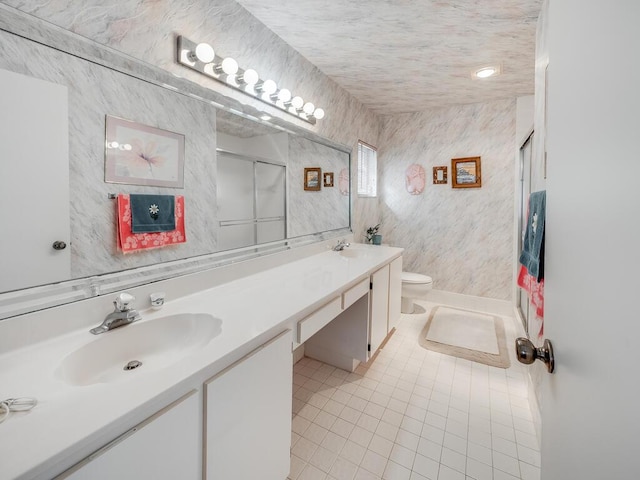 bathroom with tile patterned floors, toilet, a sink, a shower stall, and double vanity