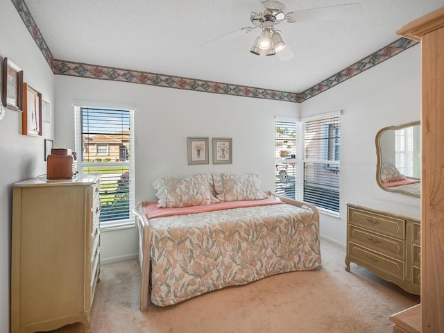 bedroom with baseboards, light carpet, a textured ceiling, and ceiling fan