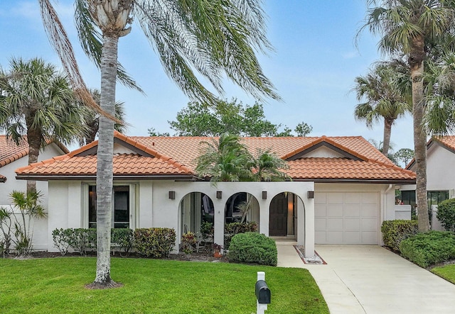 mediterranean / spanish-style home with stucco siding, a tiled roof, concrete driveway, and a front yard