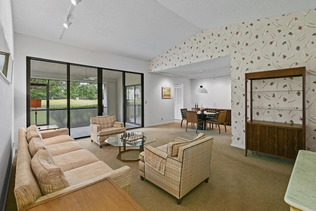 living area with wallpapered walls, lofted ceiling, carpet flooring, rail lighting, and a textured ceiling