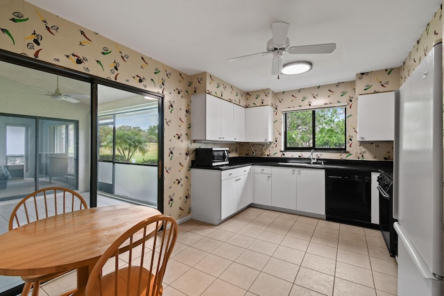 kitchen featuring dark countertops, wallpapered walls, white cabinets, black appliances, and a ceiling fan