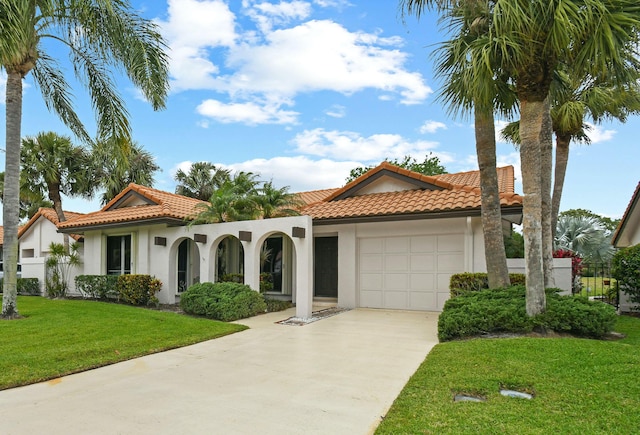 mediterranean / spanish home with driveway, an attached garage, stucco siding, a front lawn, and a tile roof