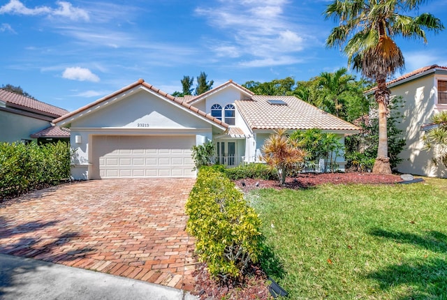 mediterranean / spanish-style home with a tile roof, a front yard, stucco siding, a garage, and driveway