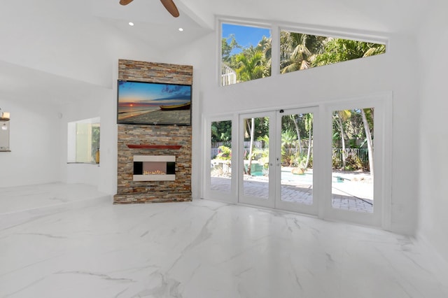 unfurnished living room featuring a ceiling fan, recessed lighting, a fireplace, a towering ceiling, and marble finish floor