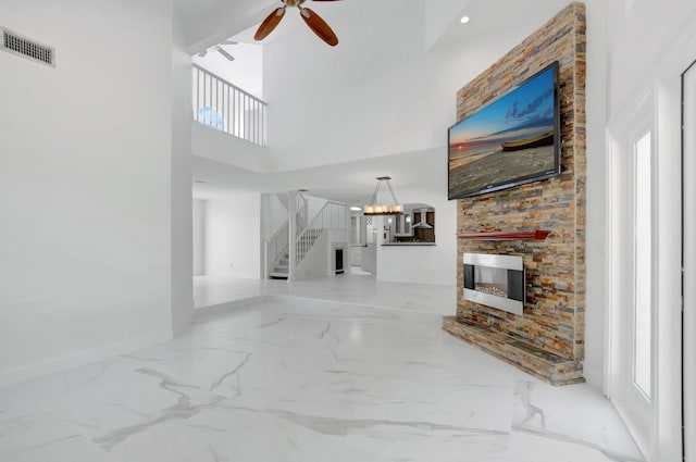 living room with stairway, a ceiling fan, visible vents, a stone fireplace, and marble finish floor