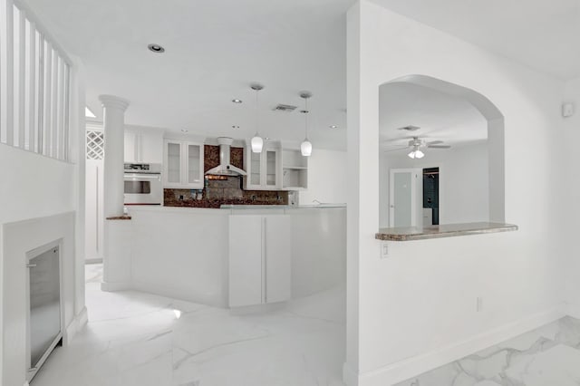 kitchen with visible vents, glass insert cabinets, wall chimney range hood, stainless steel oven, and marble finish floor