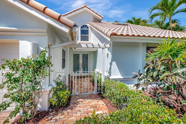 property entrance featuring a tile roof, french doors, and stucco siding