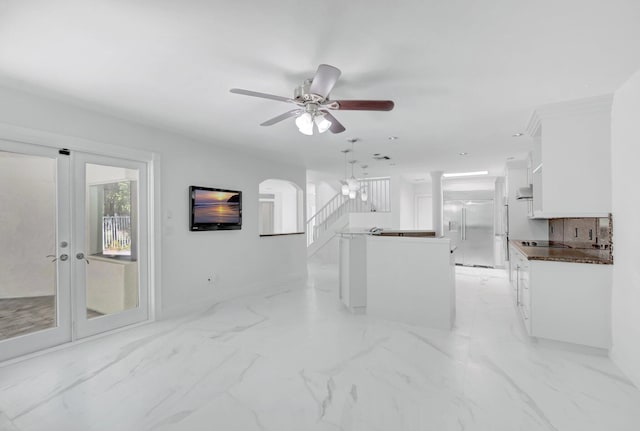 living area with a ceiling fan, marble finish floor, french doors, and arched walkways