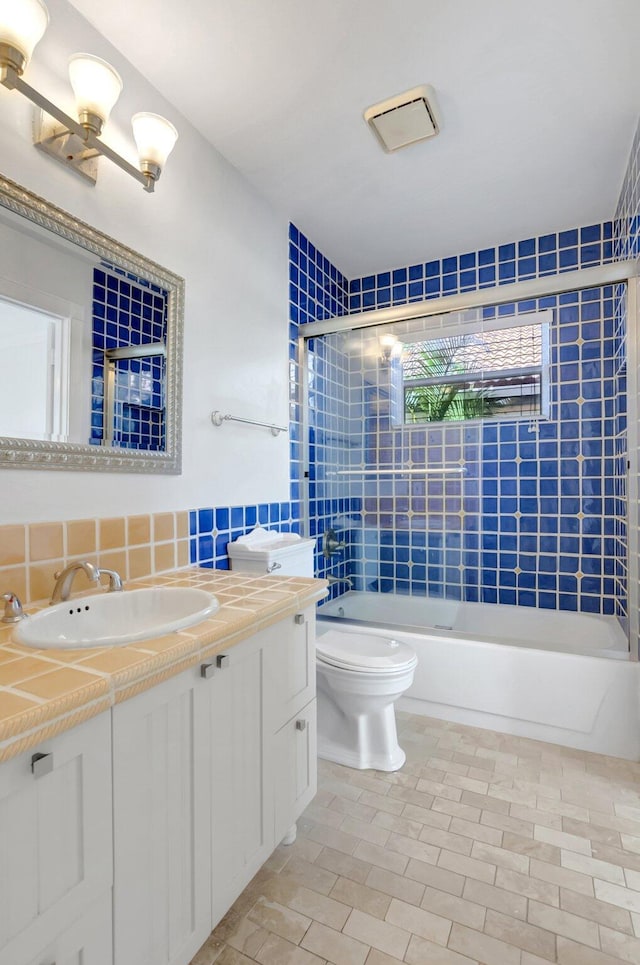 bathroom featuring backsplash, toilet, vanity, and bathing tub / shower combination