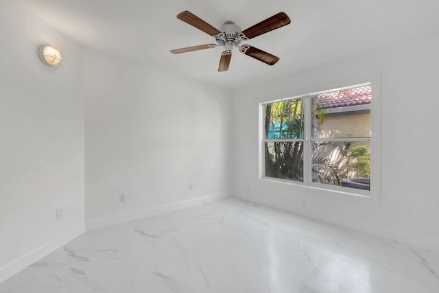 spare room with marble finish floor, baseboards, and ceiling fan