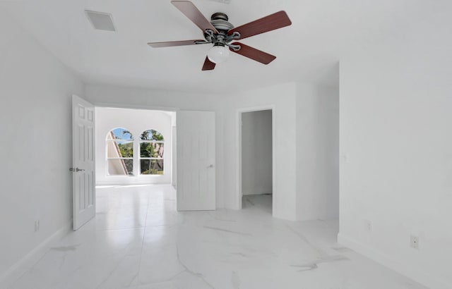 spare room with marble finish floor, baseboards, and ceiling fan