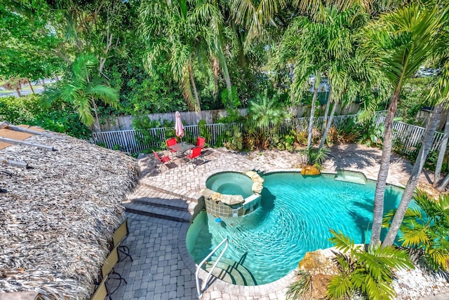 view of swimming pool with a patio, a fenced backyard, and a pool with connected hot tub